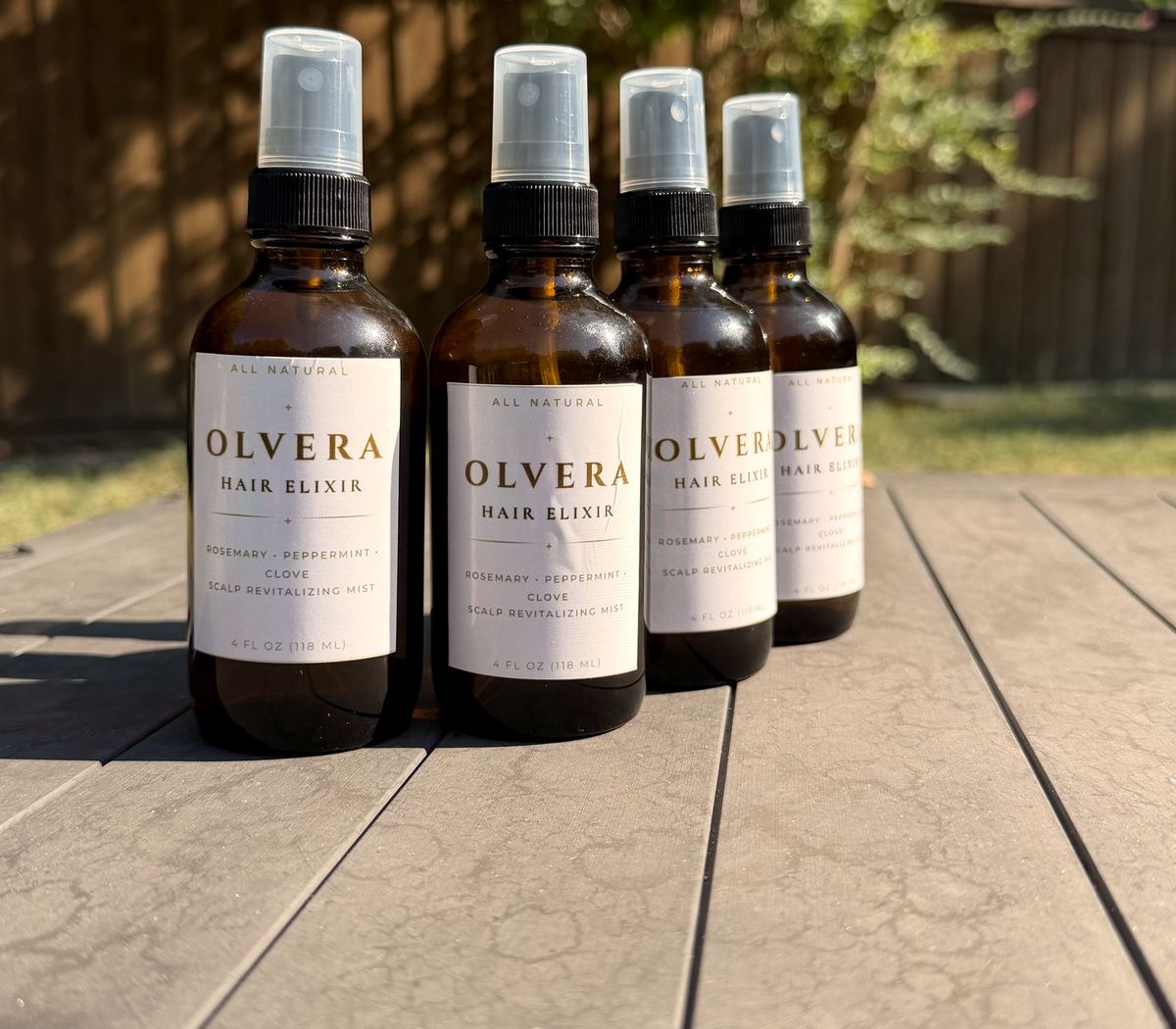 Four bottles of OLVERA Hair Elixir on a table in Dallas
